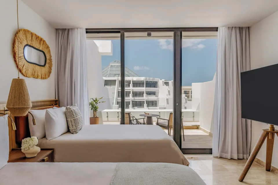 Family Concierge Junior Suite Sunset View bedroom and balcony at Paradisus Cancún.