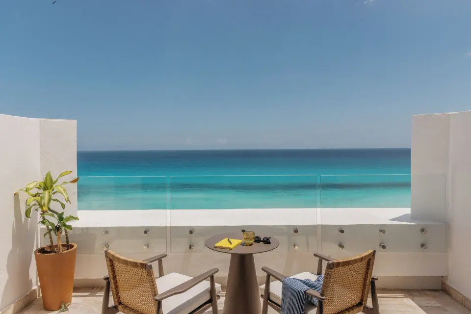 Governor Suite balcony with two chairs, table and ocean view at Paradisus Cancún.