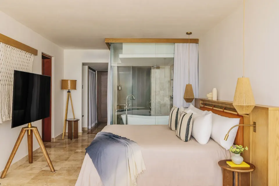 King bed, TV and glass-walled bath in The Reserve Suite Sunset View Adults Only at Paradisus Cancún.