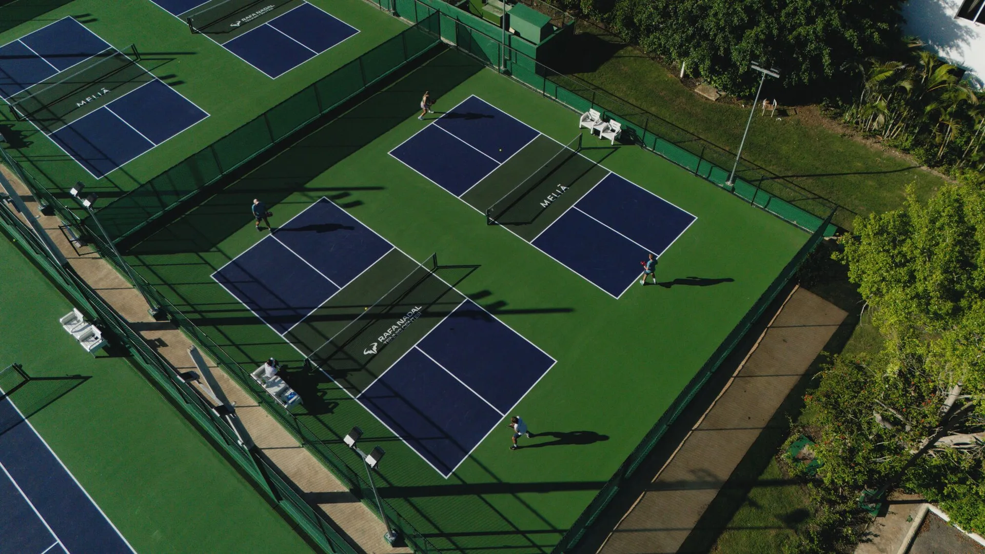 Aerial view of multiple tennis courts with players at Paradisus Grand Cana.