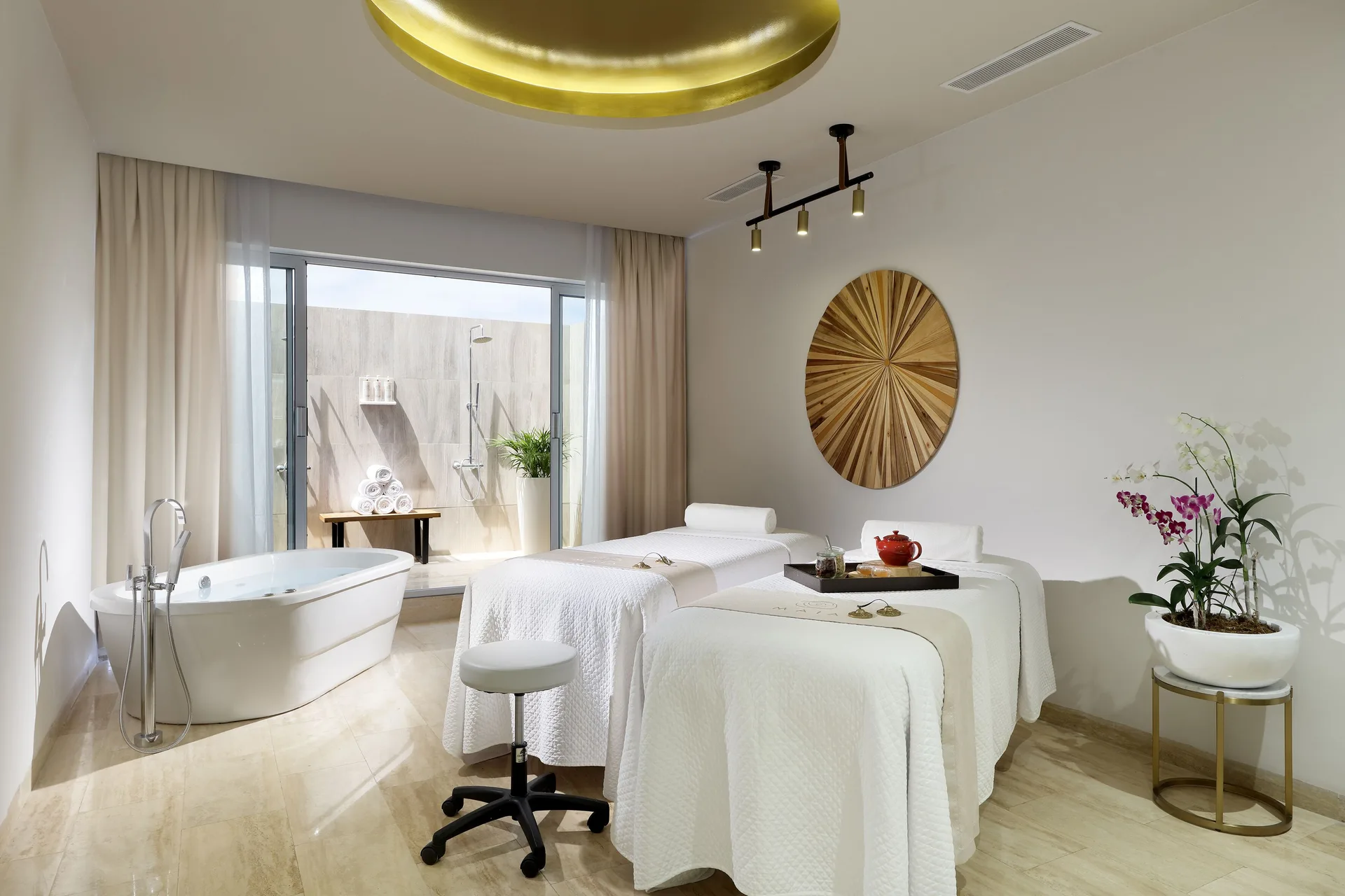 A spa treatment room with two massage tables and a bathtub at Paradisus Grand Cana.