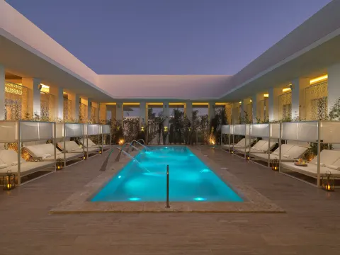 An illuminated courtyard pool with daybeds at dusk at Paradisus Grand Cana.
