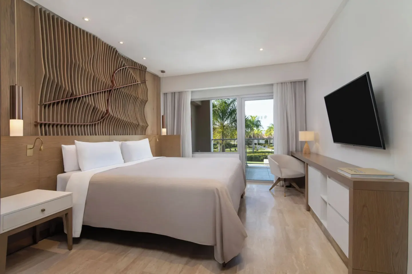 King bed guest room with desk and balcony doors at Paradisus Grand Cana.