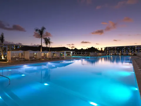 Illuminated resort pool at dusk with cabanas at Paradisus Grand Cana.
