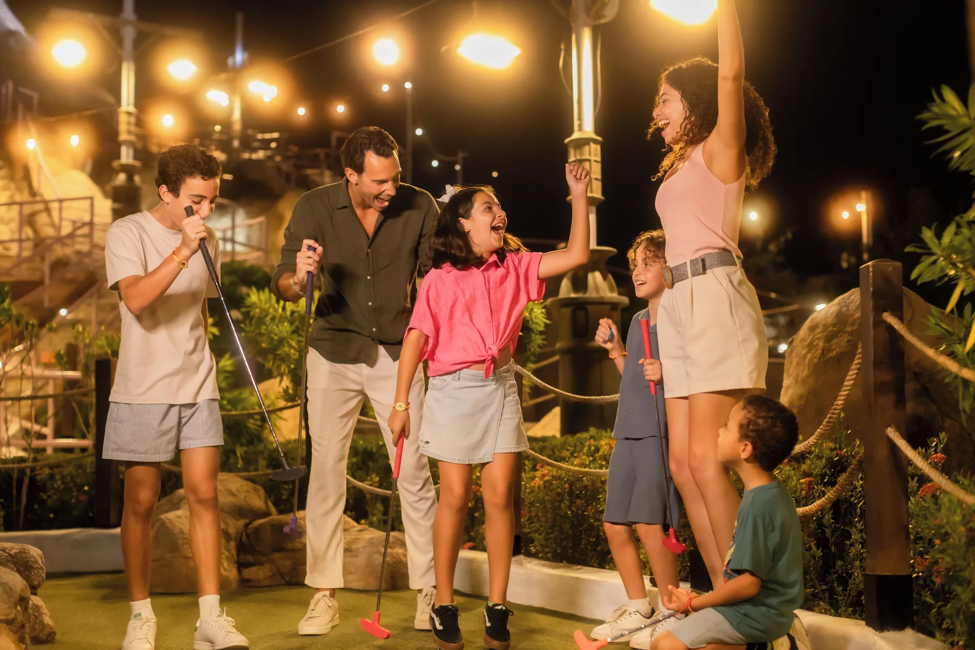 Family celebrating while playing mini golf at night at Paradisus Grand Cana.