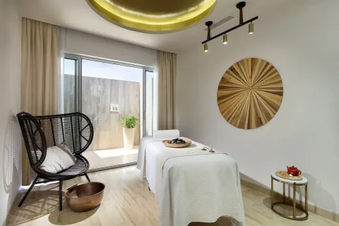 A spa room with a massage table, chair, and outdoor shower at Paradisus Grand Cana.