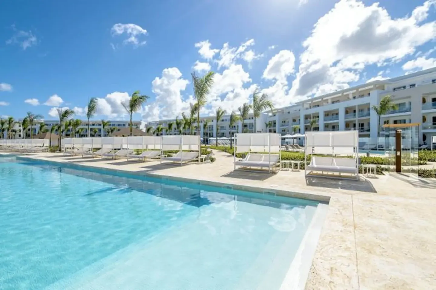 Sunny pool deck with cabanas and resort buildings at Paradisus Grand Cana.