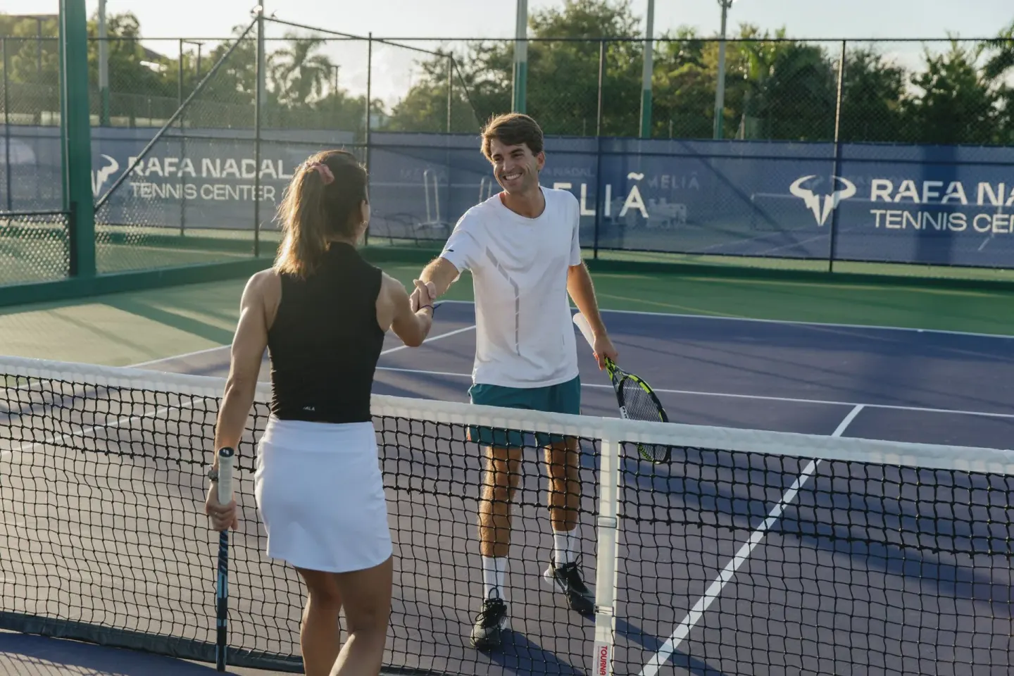 Two tennis players shake hands across the net at Paradisus Grand Cana.