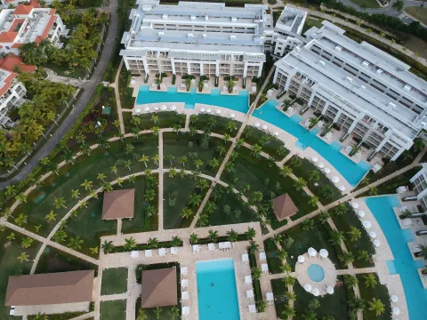 Wide aerial view of resort buildings, pools, and palm gardens at Paradisus Grand Cana.