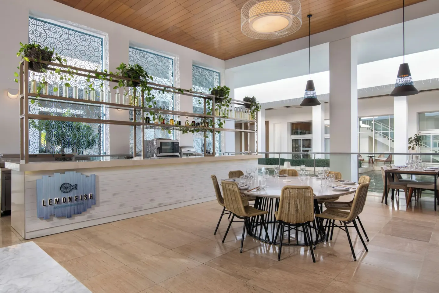 Lemon Fish dining room with round table, bar counter and greenery at Paradisus Grand Cana.