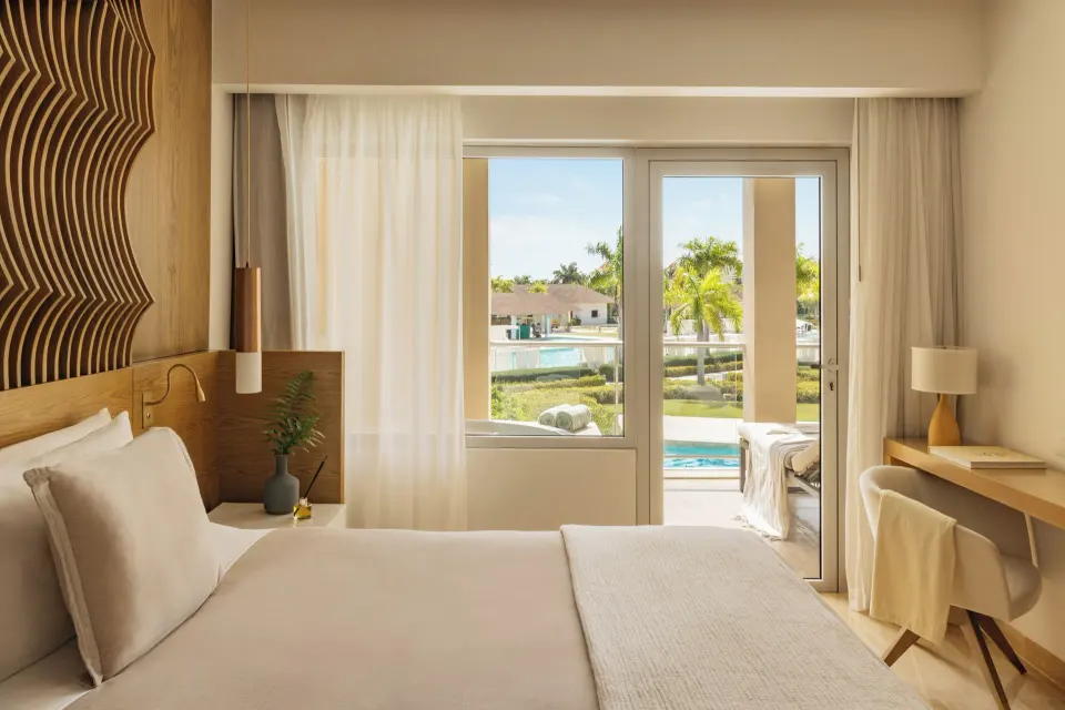 Bedroom with bed, desk, and balcony doors in the Family Concierge Master Suite at Paradisus Grand Cana.