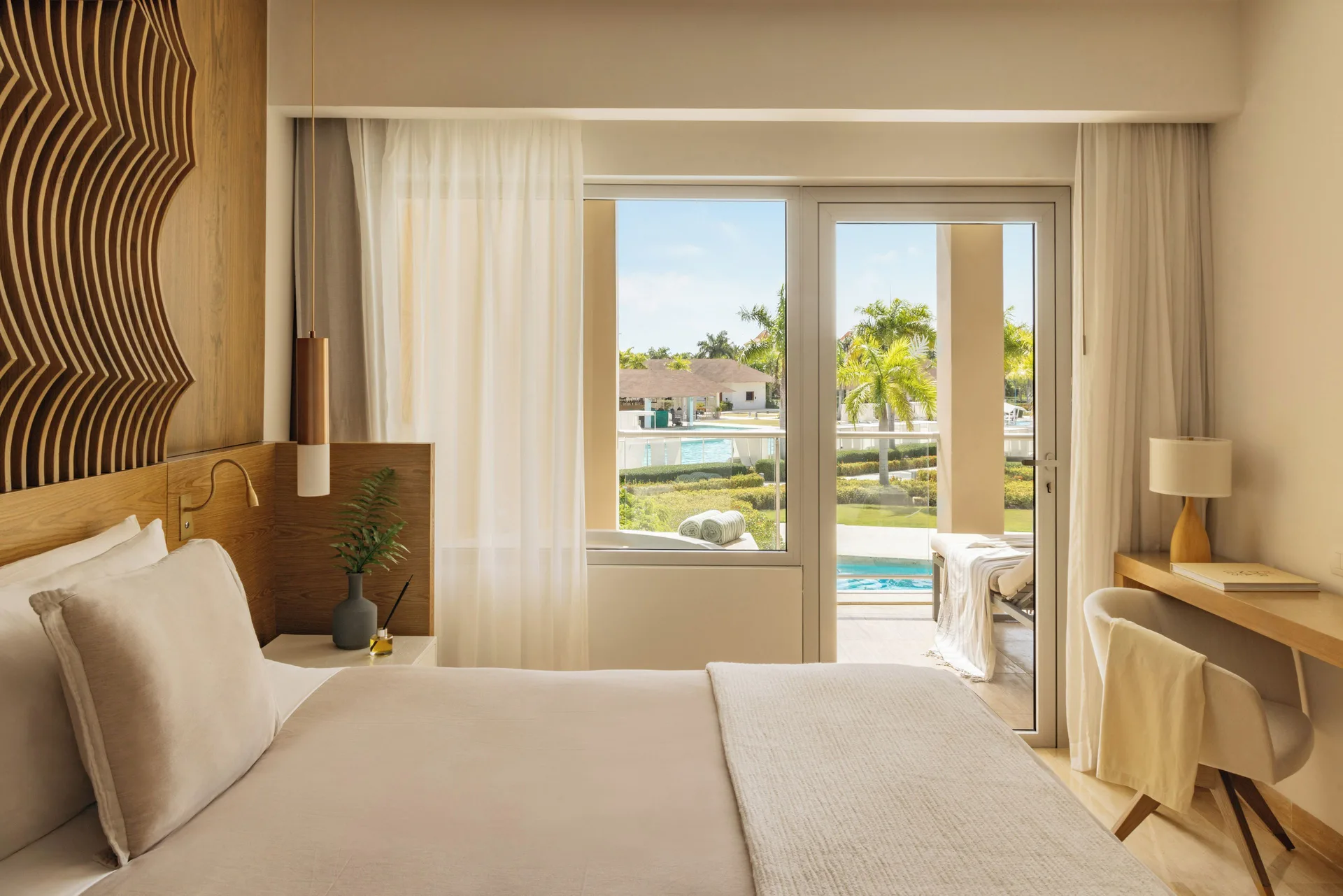 Bedroom with bed, desk, and balcony doors in the Family Concierge Master Suite at Paradisus Grand Cana.