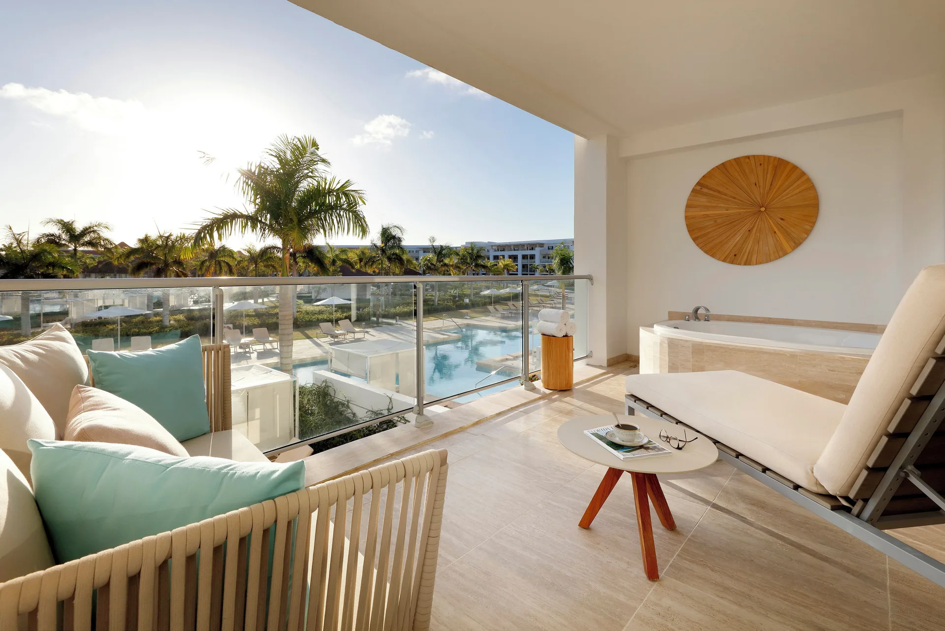 One Bedroom Suite balcony with lounger, sofa, soaking tub, and pool view at Paradisus Grand Cana.