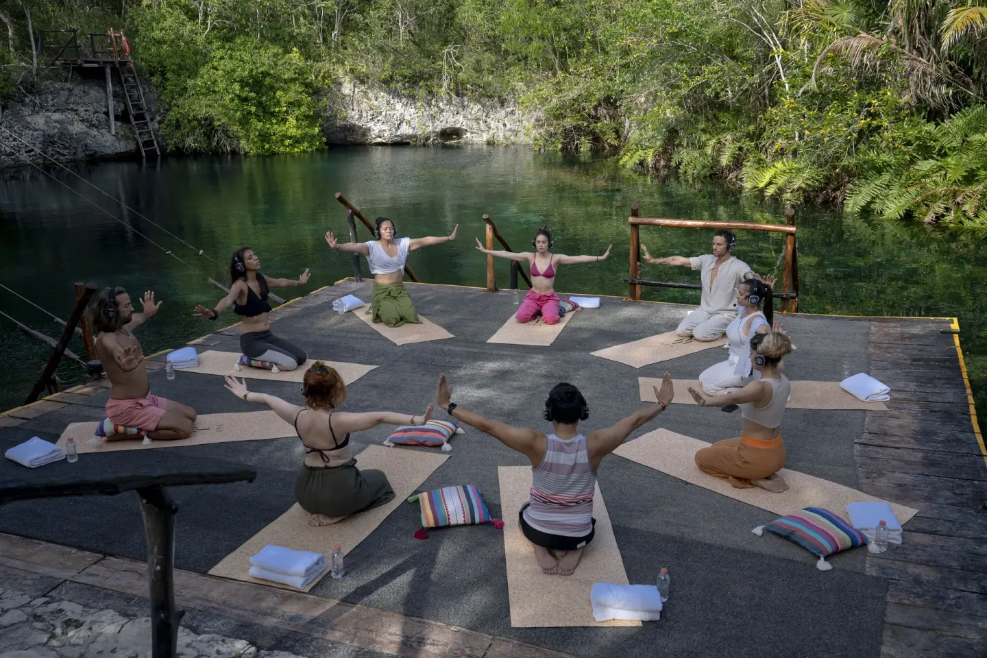 Guests practice yoga on a deck beside green water at Paradisus La Perla Riviera Maya.