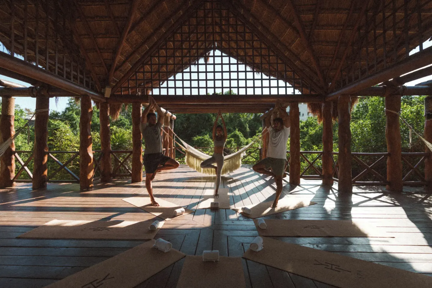 Yoga class practicing tree pose in an open-air palapa at Paradisus La Perla Riviera Maya.