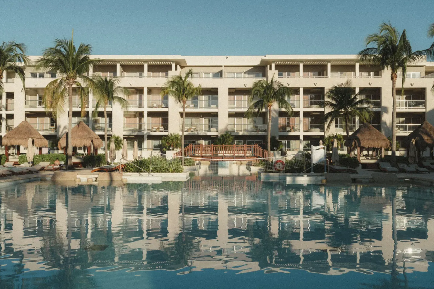 Pool reflection of palms and guest-room balconies at Paradisus La Perla Riviera Maya.