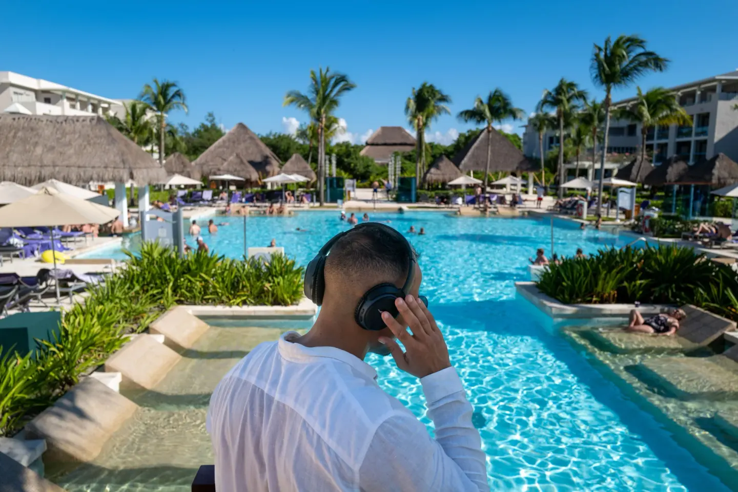 A DJ overlooks a busy pool scene at Paradisus La Perla Riviera Maya.