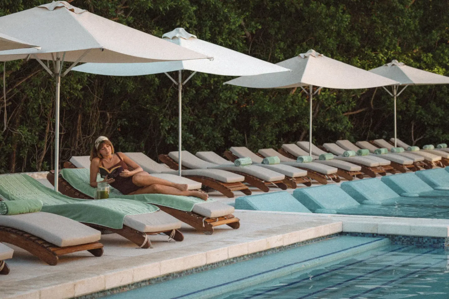 A guest reads on a poolside lounger at Paradisus La Perla Riviera Maya.