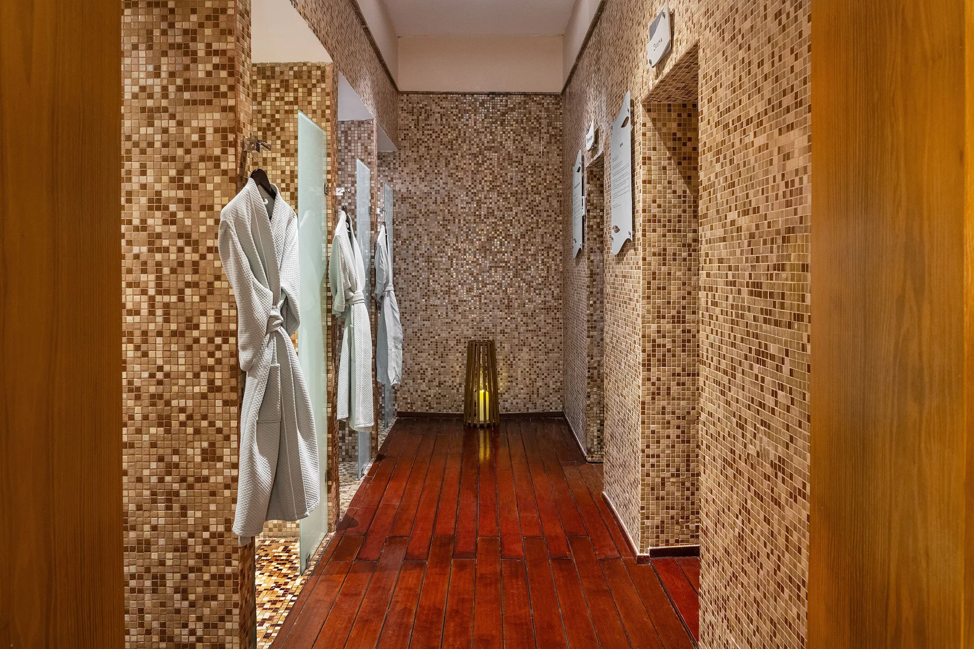 Spa corridor with mosaic tile walls and hanging robes at Paradisus La Perla Riviera Maya.