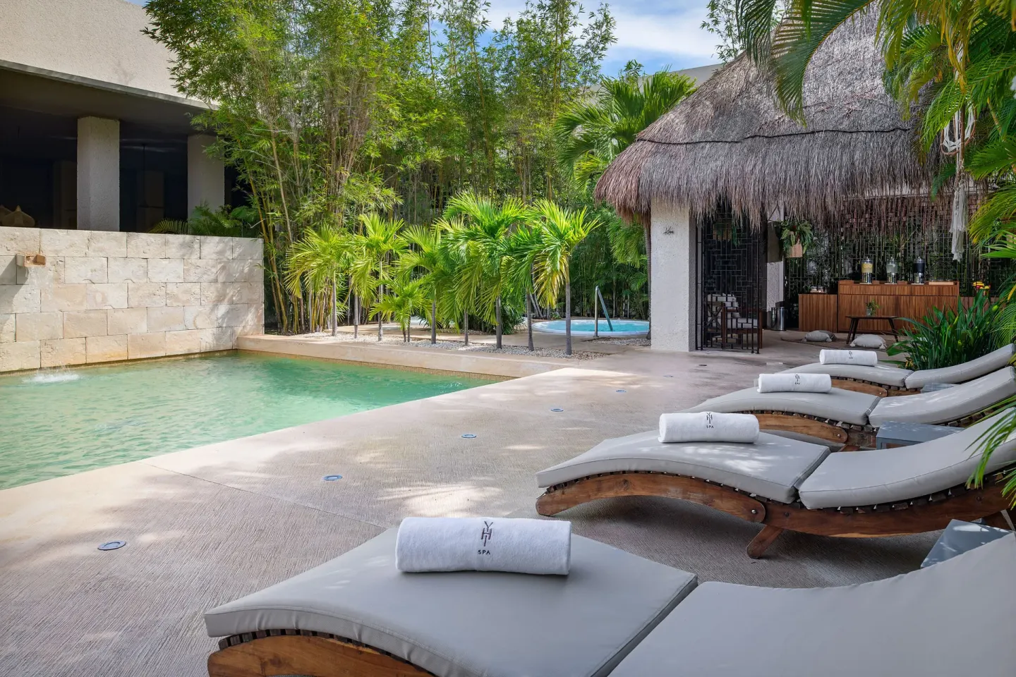Spa poolside loungers beside tropical greenery at Paradisus La Perla Riviera Maya.