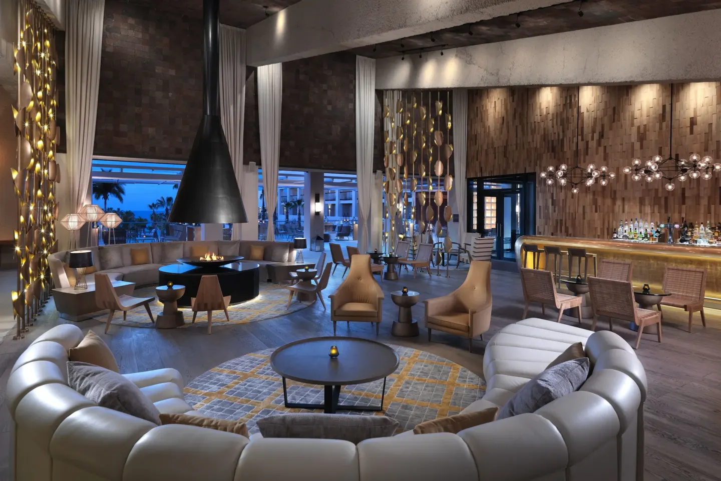 Lounge seating, bar, and central fireplace in the lobby at Paradisus Los Cabos.