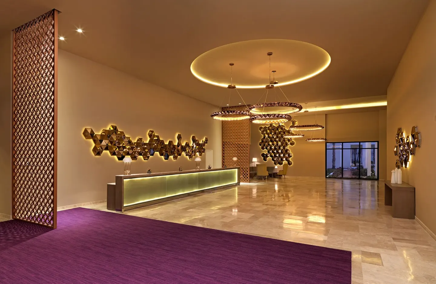 Lobby reception desk with warm lighting and purple carpet at Paradisus Los Cabos.
