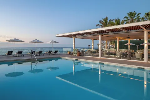 Pool beside an open-air terrace and ocean at Paradisus Los Cabos.