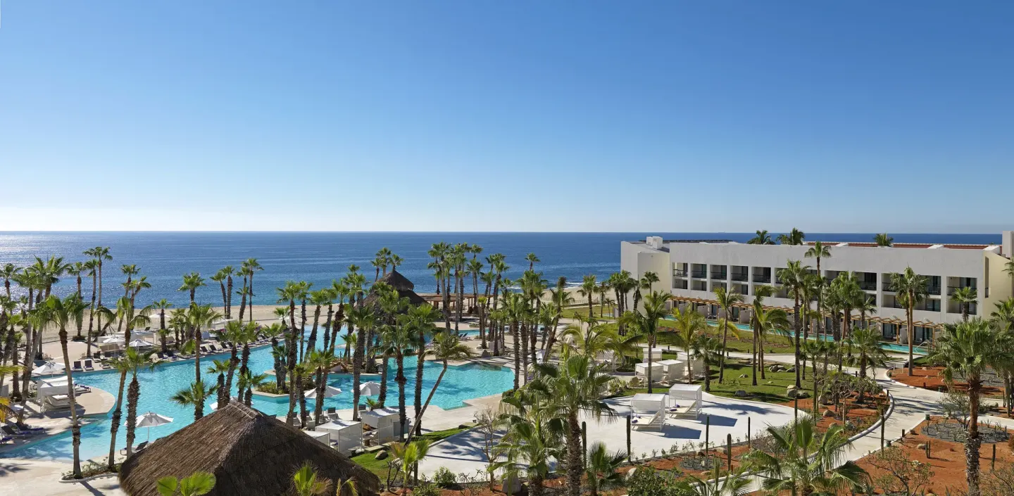 Resort pools, palms, and oceanfront buildings at Paradisus Los Cabos.