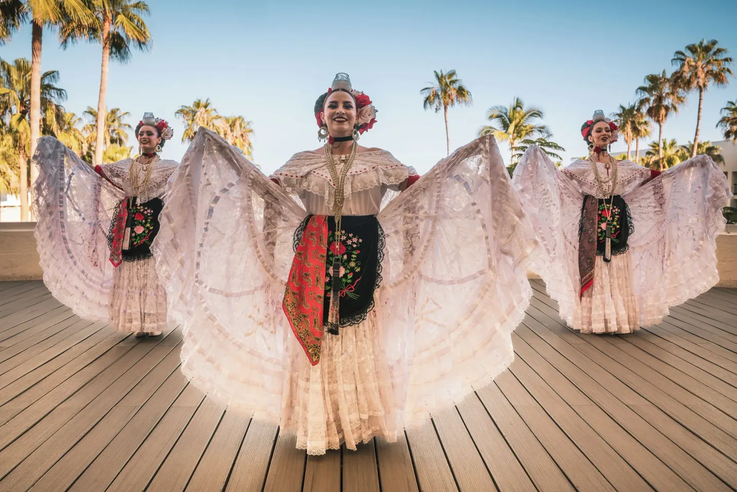 Traditional dancers in colorful dresses on an outdoor deck at Paradisus Los Cabos.
