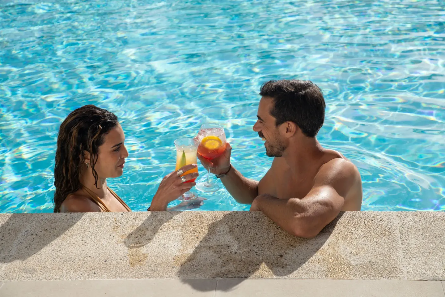 Couple toast cocktails while standing in the pool at Paradisus Los Cabos.