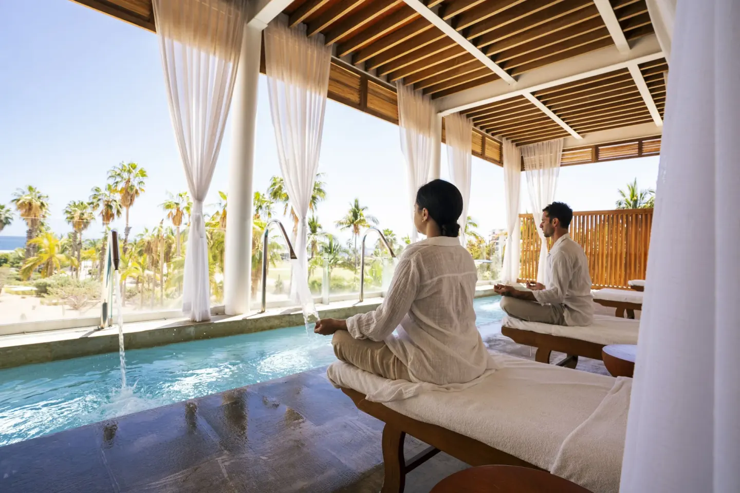 Guests meditating beside a narrow spa pool at Paradisus Los Cabos.