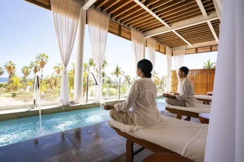 Guests meditating beside a narrow spa pool at Paradisus Los Cabos.