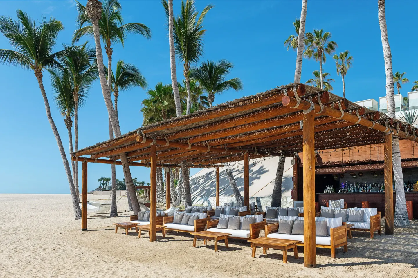 Beach lounge bar with sofas under a pergola at Paradisus Los Cabos.