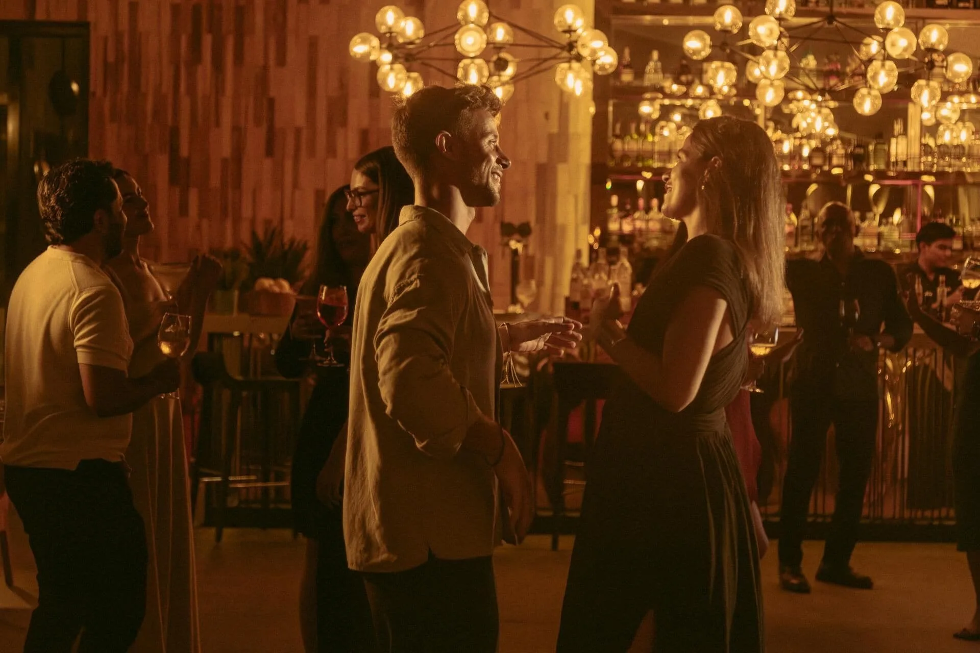 Guests socialize with drinks in a warmly lit bar at Paradisus Los Cabos.