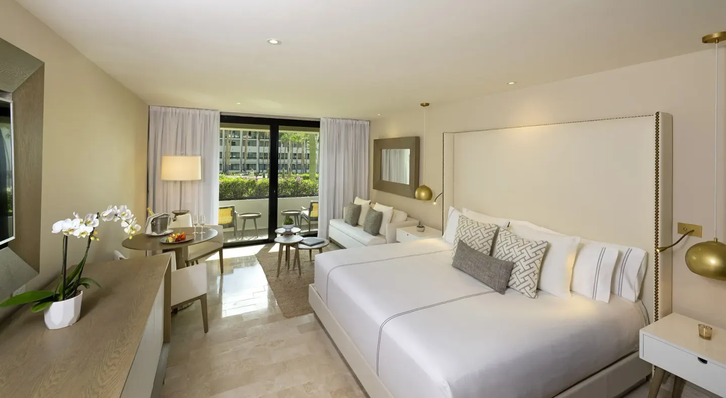 King-bed Junior Suite with sofa, balcony, and garden view at Paradisus Los Cabos.