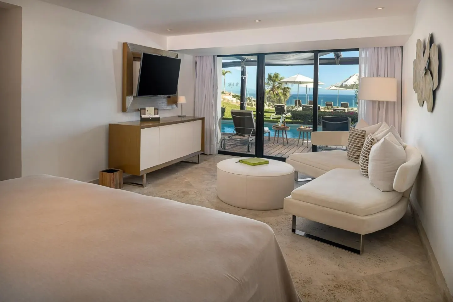 Ocean-front swim-up suite king bed and seating area at Paradisus Los Cabos.