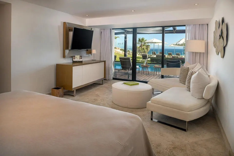 Ocean-front swim-up suite king bed and seating area at Paradisus Los Cabos.