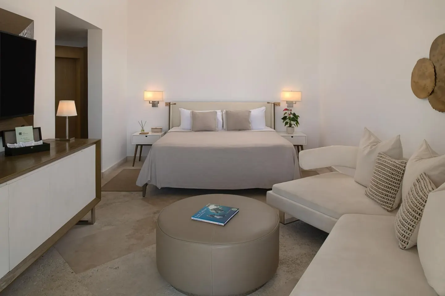 The Reserve Master Suite king bed at Paradisus Los Cabos with sofa seating, ottoman, and wall-mounted TV.