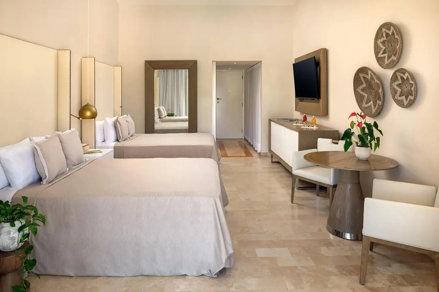 Two beds and a dining nook in The Reserve Suite Garden View at Paradisus Los Cabos.