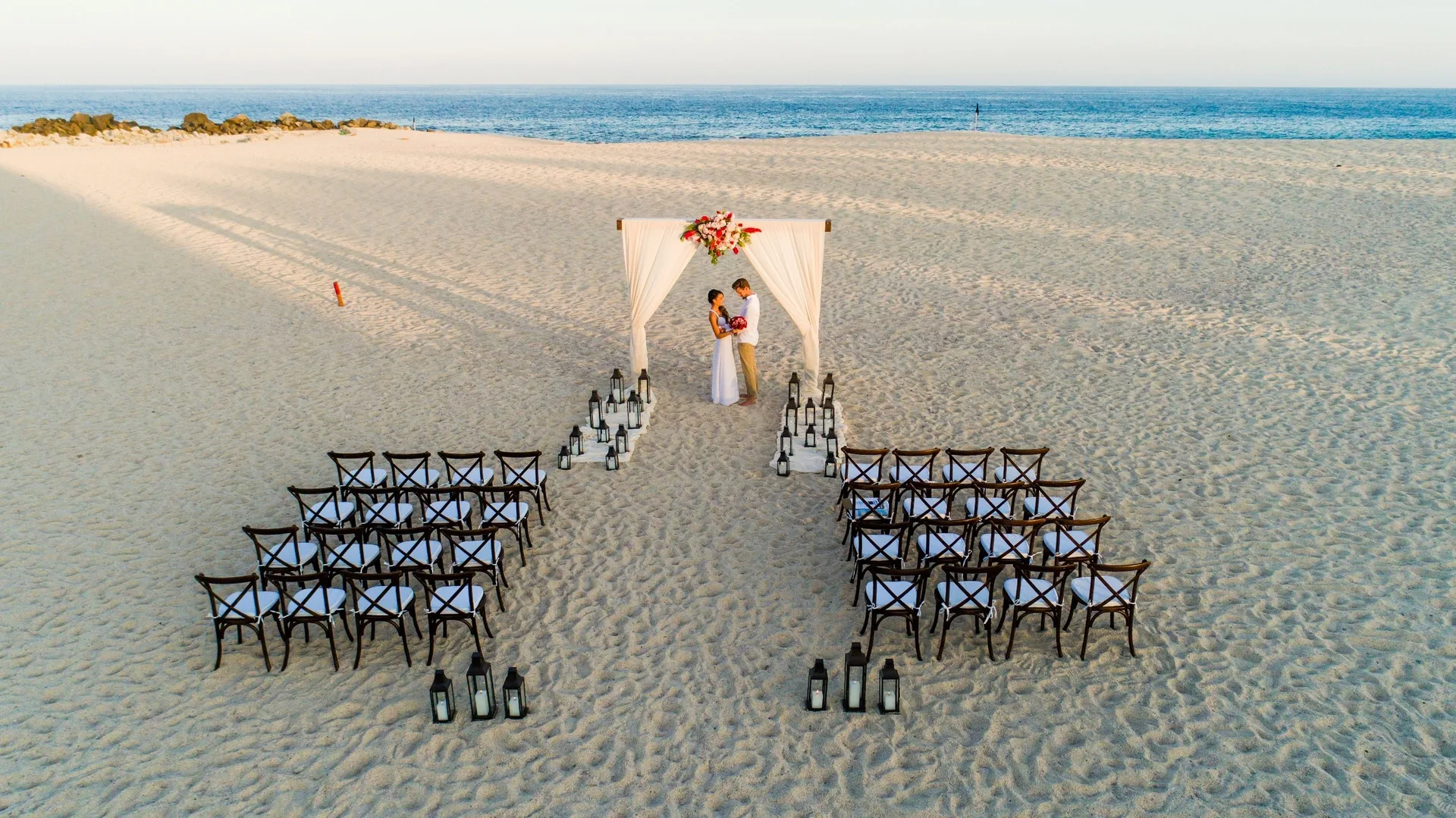 Beach wedding ceremony setup with chairs and a floral arch at Paradisus Los Cabos.