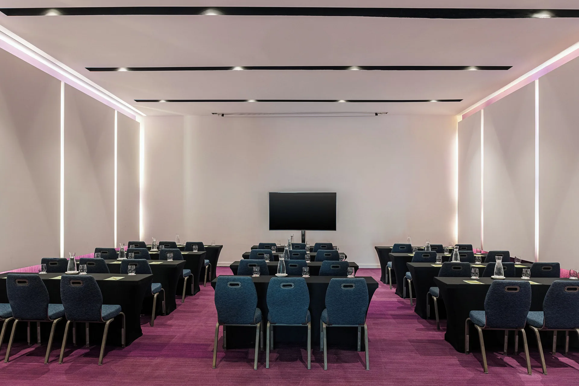 Classroom-style meeting room with rows of tables and a screen at Paradisus Los Cabos.