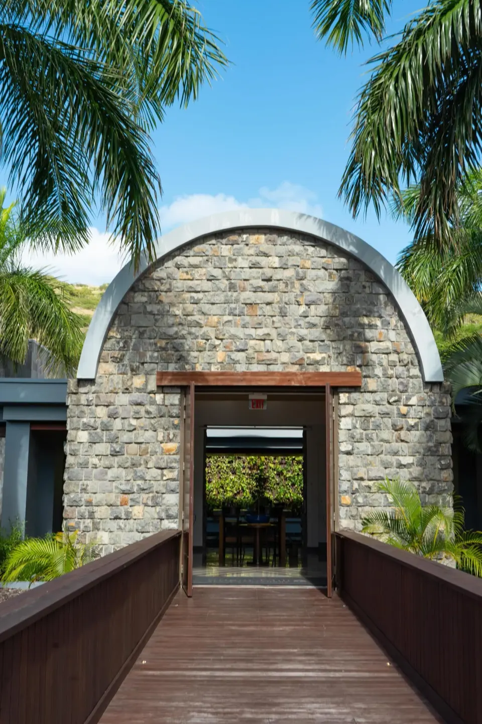 Arched stone building entrance with palm trees at Park Hyatt St. Kitts.