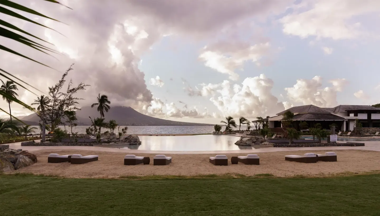 Beach daybeds face the infinity pool and cloudy sea view at Park Hyatt St. Kitts.