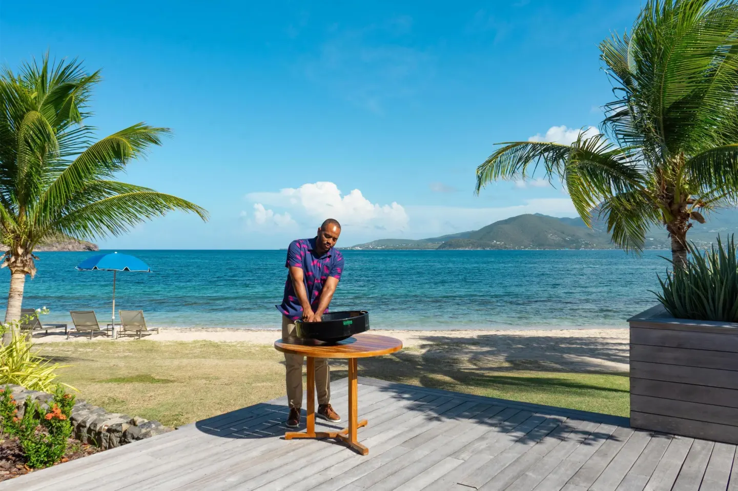 Staff member at an outdoor table by the beach at Park Hyatt St. Kitts.