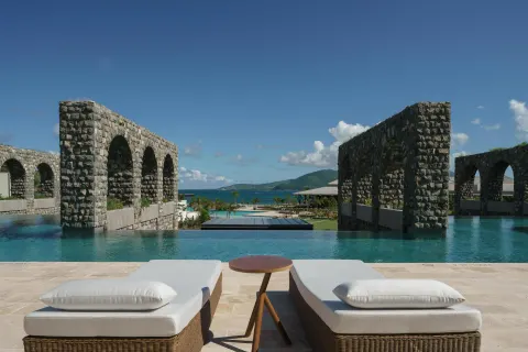 Cushioned loungers overlook a pool framed by stone arches at Park Hyatt St. Kitts.
