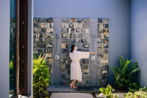 Outdoor shower area with stone wall and tropical plants at Park Hyatt St. Kitts.