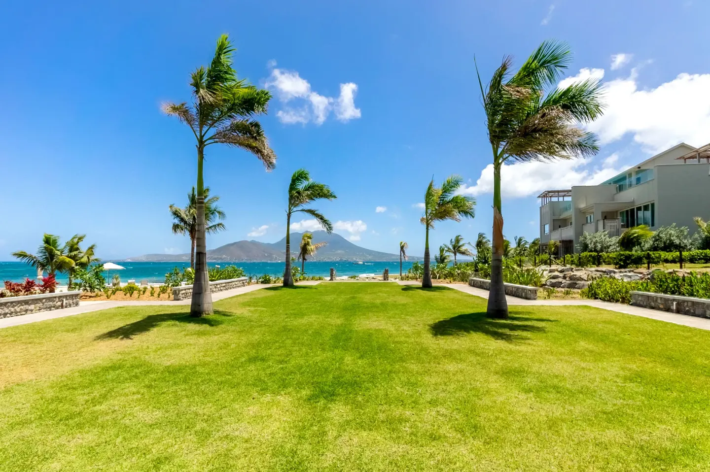 Palm lawn with ocean and island views beside guest buildings at Park Hyatt St. Kitts.