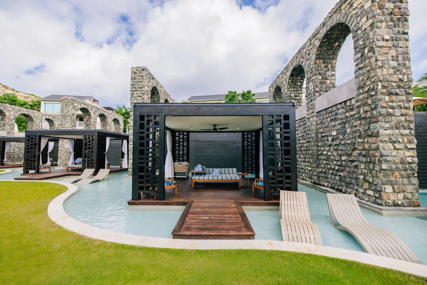 Cabana over shallow pool water beside stone arches at Park Hyatt St. Kitts.