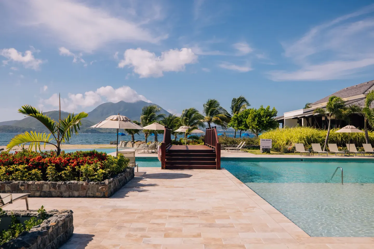 Resort pool terrace with bridge, palms, and ocean backdrop at Park Hyatt St. Kitts.