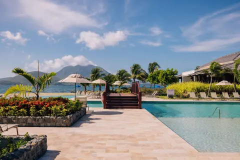 Resort pool terrace with bridge, palms, and ocean backdrop at Park Hyatt St. Kitts.